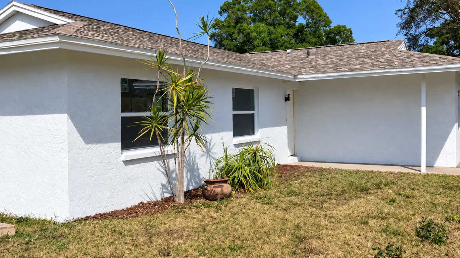 The same home after painting, clean white stucco and trim