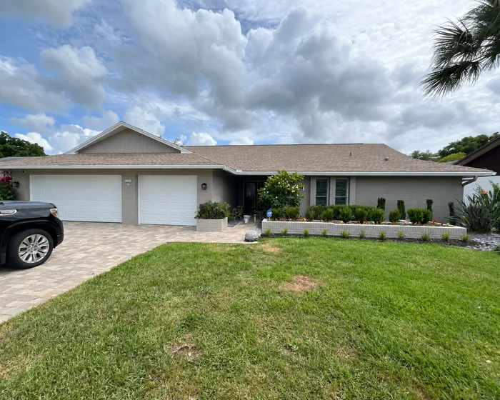 Grey painted ranch home with white garage doors, shot from the driveway